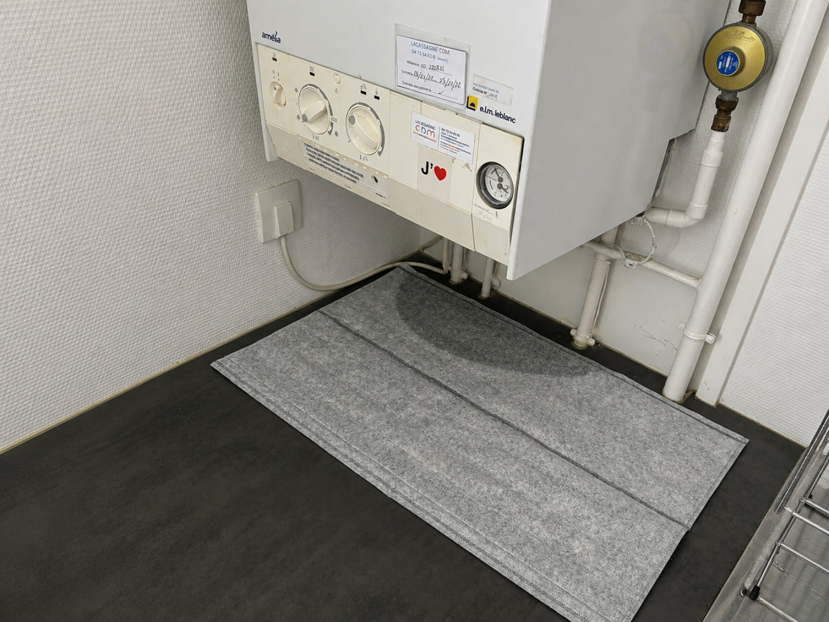 Installation d'un sac OBLOC® absorbant sous un chauffe-eau qui présente une fuite